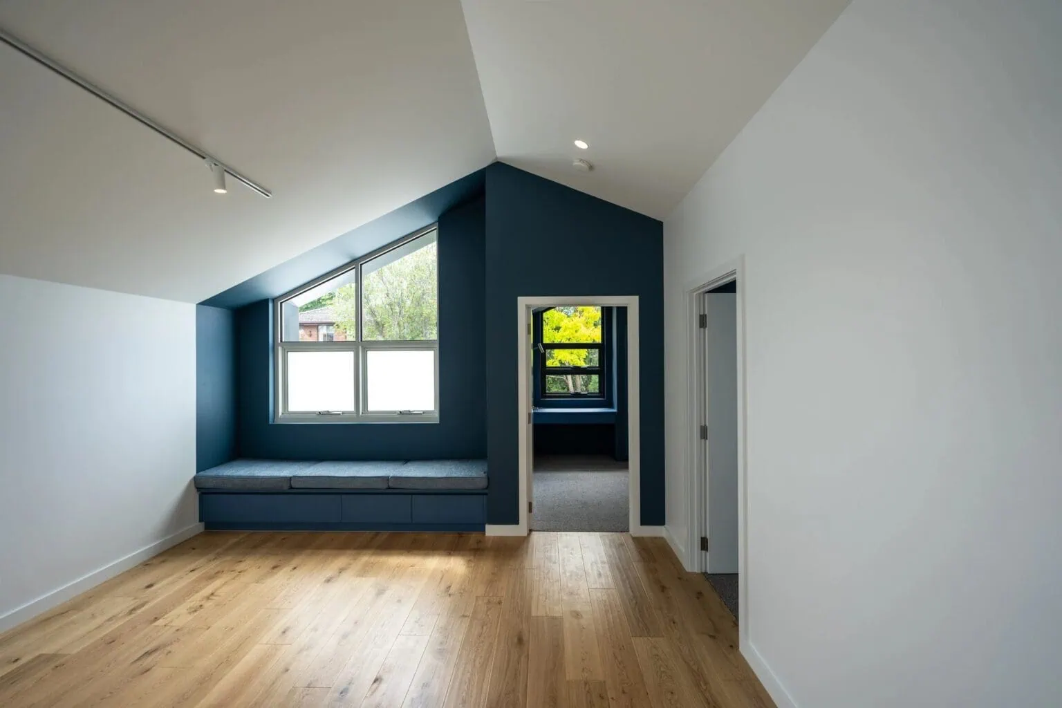 Renovated upstairs living space with a navy built-in window seat and oak flooring in a Melbourne home by Quickset Carpentry
