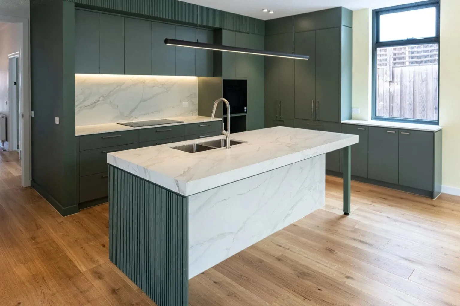 Modern kitchen renovation with dark green cabinetry and a marble waterfall island, Melbourne, by Quickset Carpentry